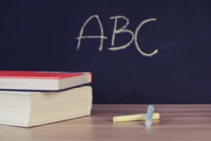 Eine Tafel, auf der "ABC" geschrieben wurde, im Vordergurnd Kreide und Bücher